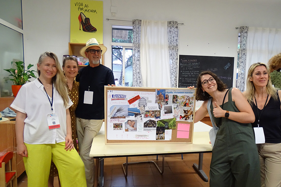 Cinque persone sorridono attorno a un cartellone ricco di immagini e scritte, realizzato durante un workshop su rigenerazione urbana, in una stanza luminosa con lavagna e poster sullo sfondo